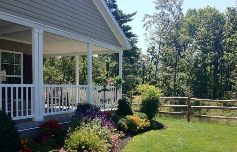 A house with flowers and trees in the yard.