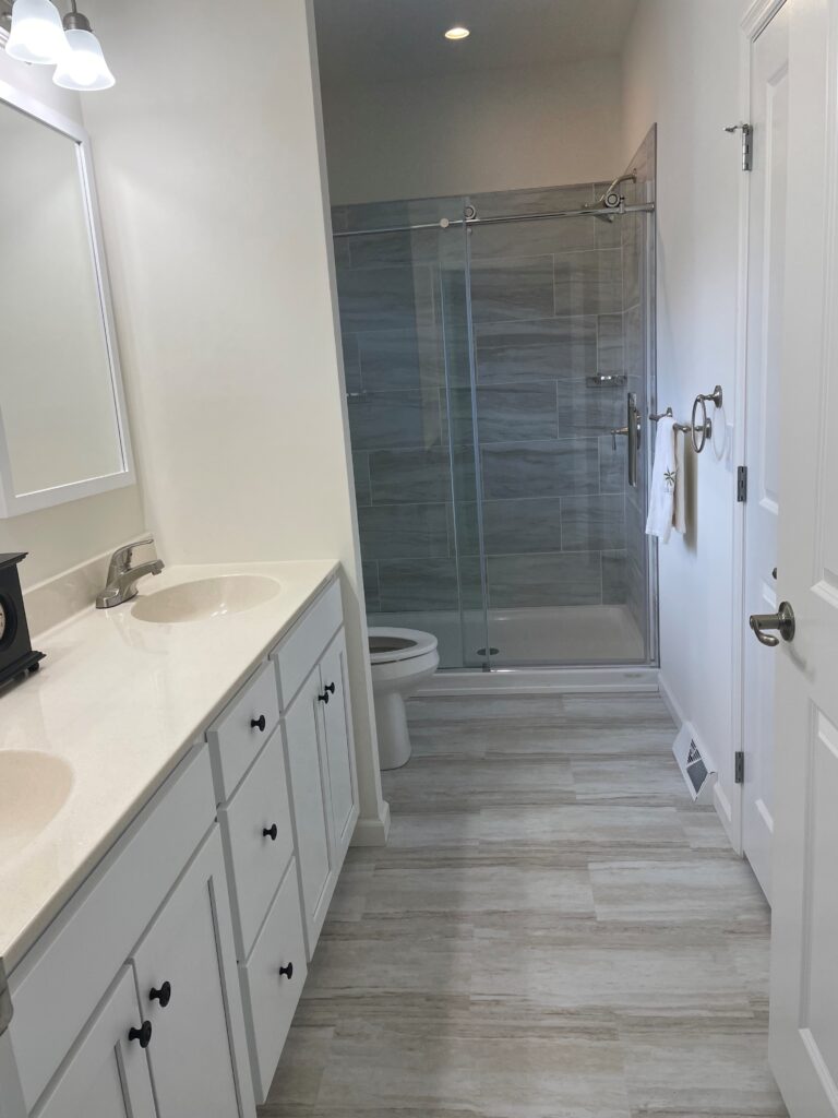 A bathroom with two sinks and a walk in shower.