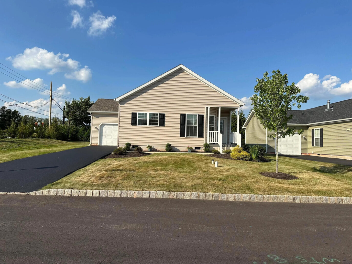 Tan house with driveway and lawn.